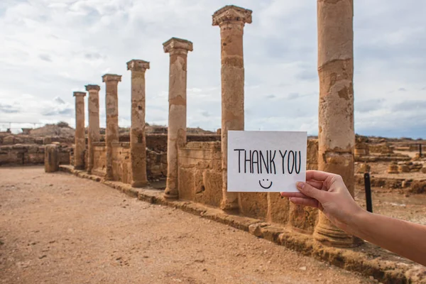 Cropped view of woman holding paper with thank you lettering near columns and walls of ancient House of Theseus — Stock Photo