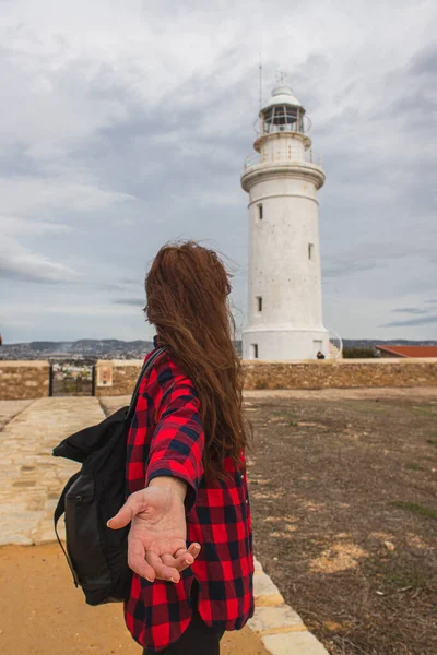 Rückansicht einer Frau mit ausgestreckter Hand, die in der Nähe des weißen Leuchtturms steht — Stockfoto