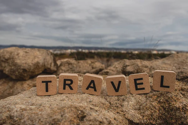 Holzwürfel mit Reisebuchstaben auf Steinen gegen den Himmel — Stockfoto