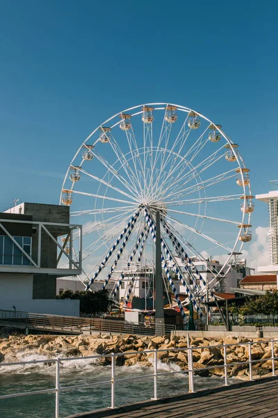 Ferris wheel near building and mediterranean sea — Stock Photo