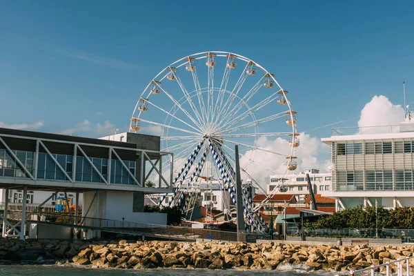 Ferris wheel near building against blue sky — Stock Photo