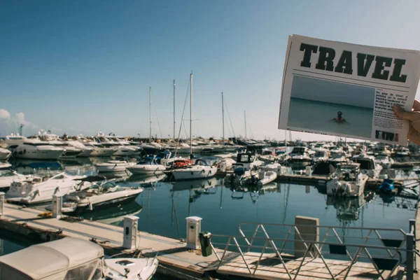 Cropped view of woman holding travel newspaper near docked ships in mediterranean sea — Stock Photo