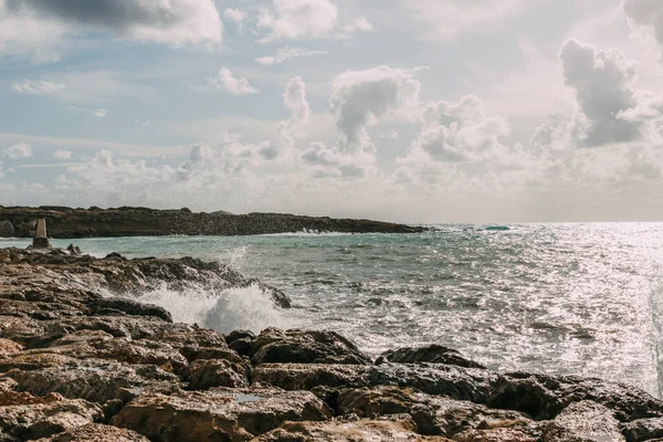 Pietre bagnate vicino al Mar Mediterraneo contro il cielo blu con nuvole — Foto stock