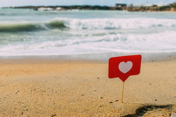 Cuore rosso su bastone su sabbia vicino a mare mediterraneo — Foto stock