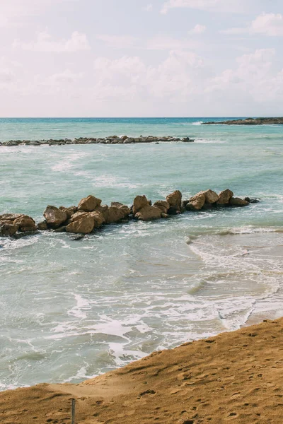 Мокрые камни в голубом средиземноморском море против неба с облаками — стоковое фото