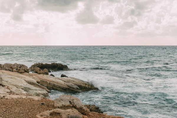 Costa con piedras cerca del mar Mediterráneo contra el cielo con nubes - foto de stock