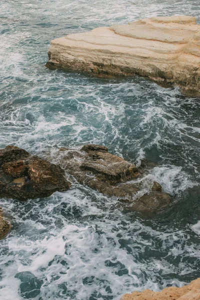 Schiuma bianca vicino a scogli in acqua azzurra di mare mediterraneo — Foto stock