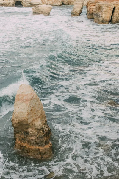 Espuma blanca cerca de piedras húmedas en el agua del mar mediterráneo en cyprus - foto de stock