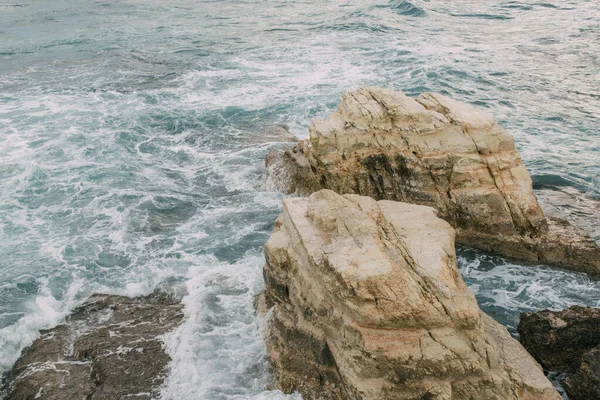 Espuma blanca cerca de rocas húmedas en el agua del mar mediterráneo en cyprus - foto de stock