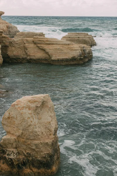 Schiuma bianca vicino a rocce in acqua di mare mediterraneo — Foto stock