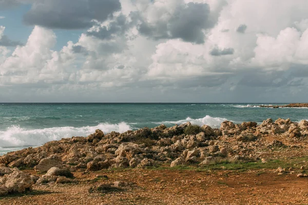 Сонячне світло на скелях біля середземного моря на тлі неба з білими хмарами — стокове фото