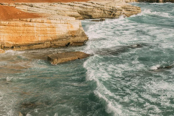 Mousse blanche près des rochers en mer bleue — Photo de stock