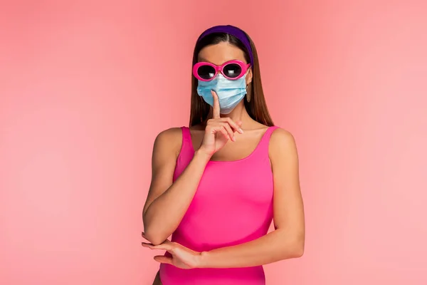 Front view of woman in sunglasses and medical mask showing shh sign isolated on pink — Stock Photo