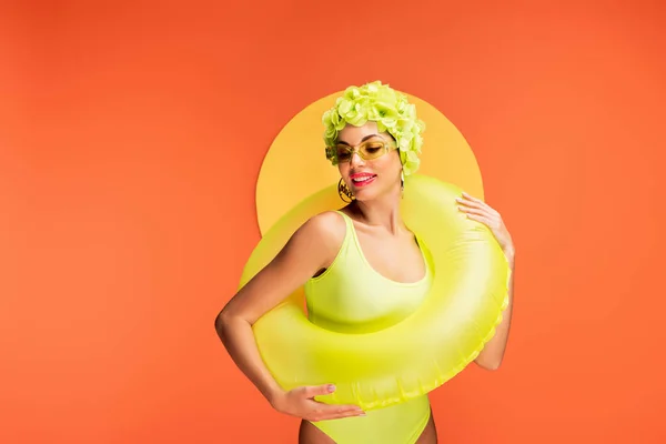 Girl with swim ring smiling on yellow and orange background — Stock Photo