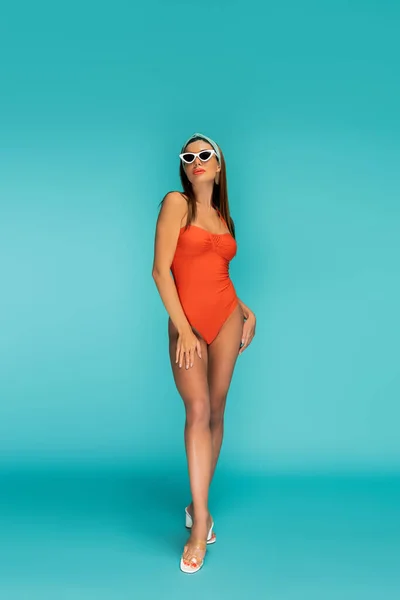 Hermosa mujer en traje de baño y gafas de sol sobre fondo azul - foto de stock
