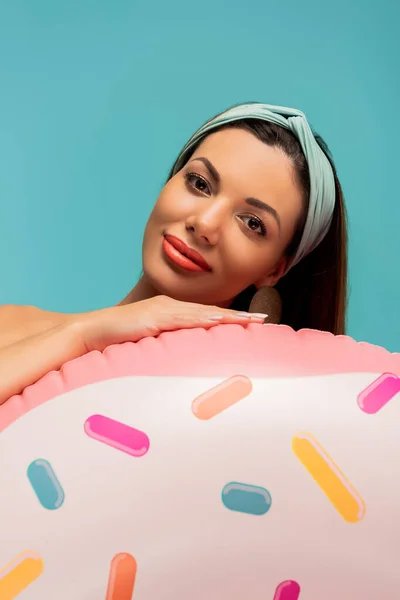 Portrait of woman with inflatable ring smiling and looking at camera isolated on blue — Stock Photo