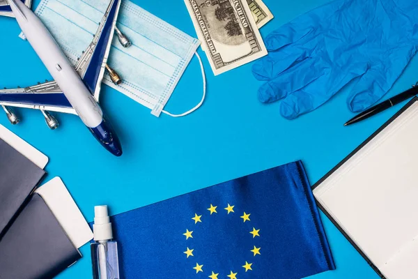 Vista superior do avião de brinquedo, máscara médica com higienizador de mão e bandeira da união europeia no fundo azul — Fotografia de Stock