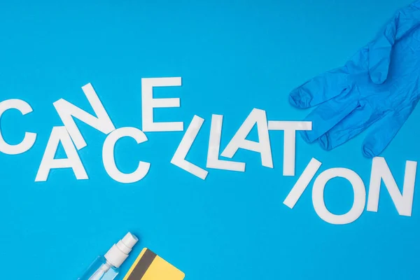 Top view of lettering cancellation with bottle of hand sanitizer, latex glove and credit card on blue background — Stock Photo
