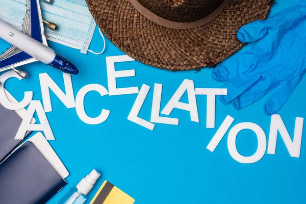 Top view of lettering cancellation near toy plane, medical mask and passports with air tickets on blue background — Stock Photo