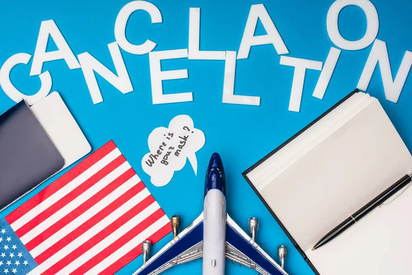 Top view of passport with air ticket, flag of america and speech bubble with where is your mask lettering near toy plane on blue surface — Stock Photo