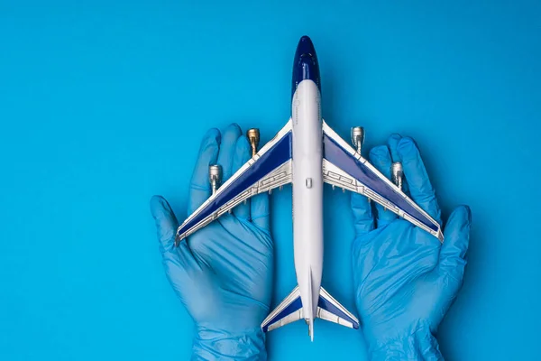 Vue du dessus du médecin en gants de latex tenant l'avion jouet sur fond bleu — Photo de stock