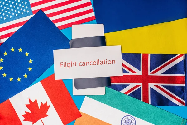 Vista dall'alto della carta con iscrizione di cancellazione del volo sul passaporto con biglietto aereo e bandiere di paesi su sfondo blu — Foto stock