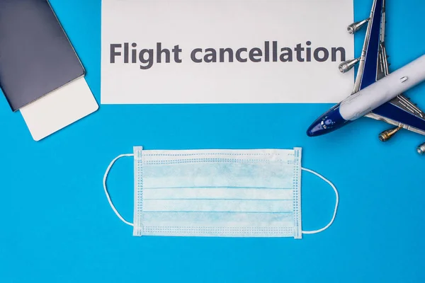 Вид сверху на медицинскую маску, паспорт с авиабилетом и карточку с отменой рейса на синей поверхности — стоковое фото