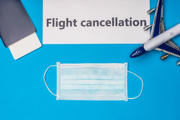 Top view of medical mask, passport with air ticket and card with flight cancellation on blue surface — Stock Photo