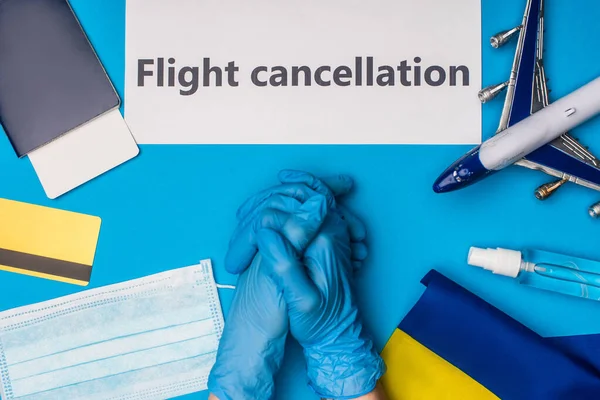 Top view of doctor near toy plane, card with flight cancellation lettering and passport with air ticket on blue background — Stock Photo