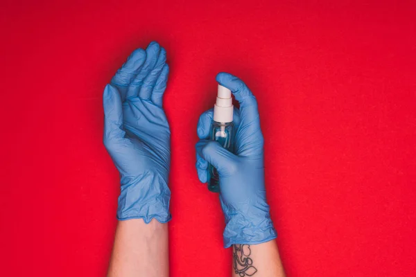 Top view of doctor in latex gloves holding hand sanitizer on red background — Stock Photo