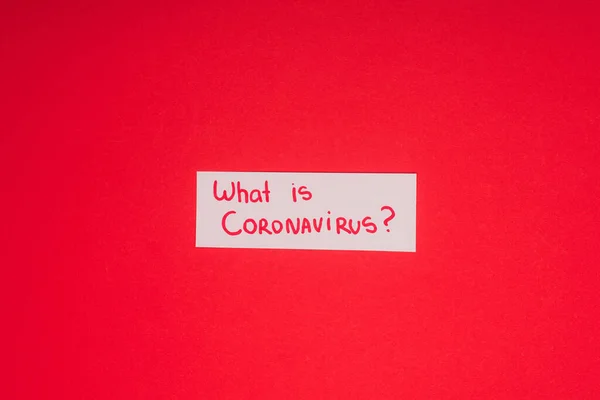 Vista superior do cartão com o que é coronavírus lettering isolado no vermelho — Fotografia de Stock