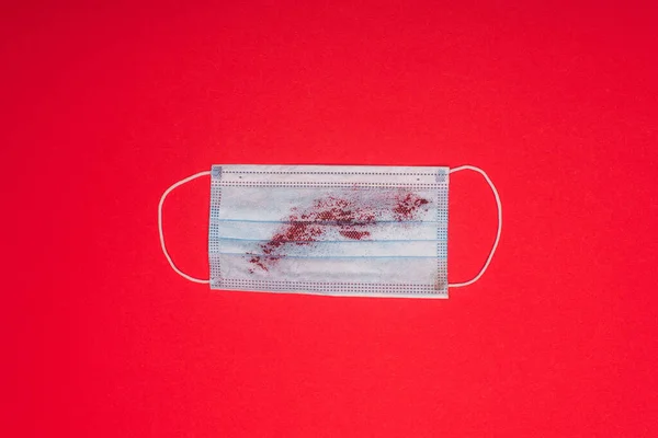 Верхний вид медицинской маски с кровью на красной поверхности — стоковое фото