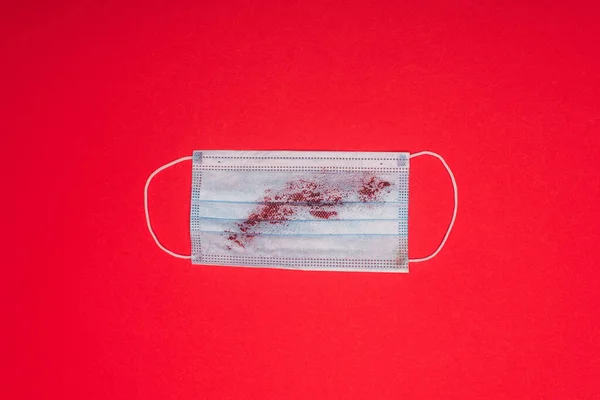 Visão superior da máscara médica com sangue na superfície vermelha — Fotografia de Stock