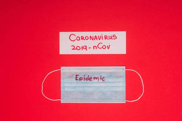 Vista superior de la máscara médica con epidemia y tarjeta con coronavirus 2019-nCov letras aisladas en rojo - foto de stock
