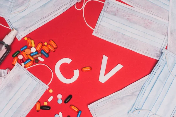 Top view of hand sanitizer, pills with medical masks and cv letters on red background — Stock Photo