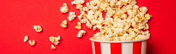 Vista dall'alto del secchio con popcorn su sfondo rosso, colpo panoramico — Foto stock