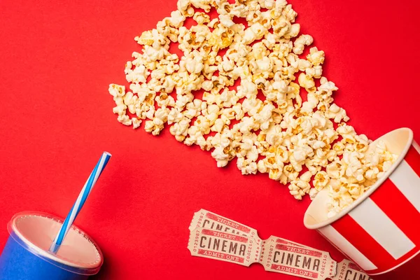 Vista superior de pipocas, bilhetes de cinema e xícara de papel na superfície vermelha — Fotografia de Stock