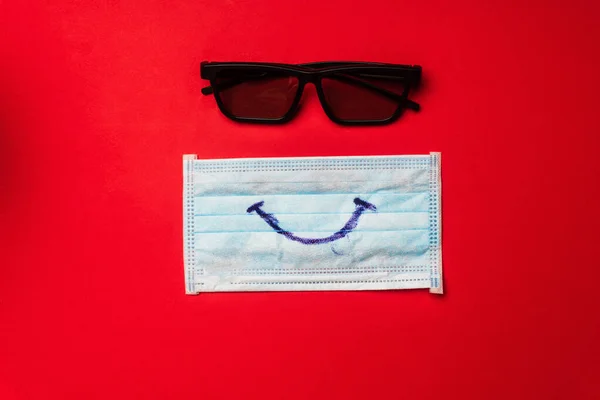 Top view of medical mask with smile and sunglasses on red background — Stock Photo