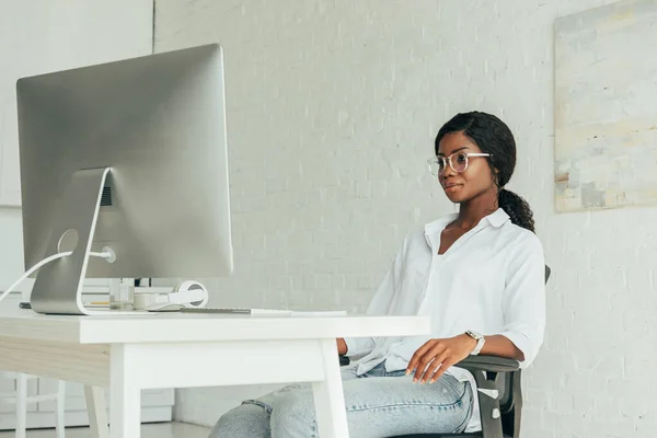 Junge, attraktive afrikanisch-amerikanische Freiberuflerin, die zu Hause auf den Computermonitor schaut — Stockfoto