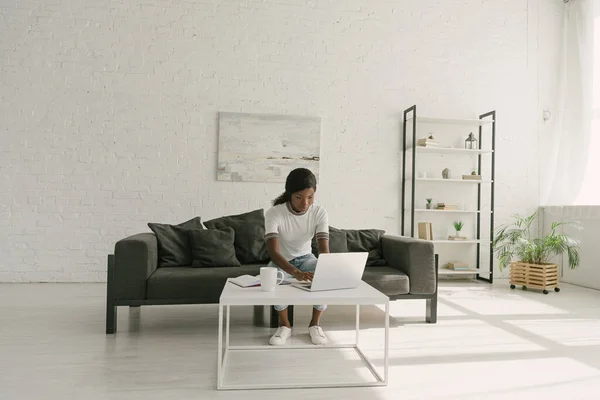 Junge afrikanisch-amerikanische Freiberuflerin arbeitet am Laptop im geräumigen Wohnzimmer — Stockfoto
