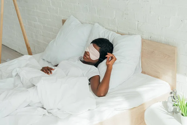 Young african american woman sleeping on white bedding in sleep mask — Stock Photo