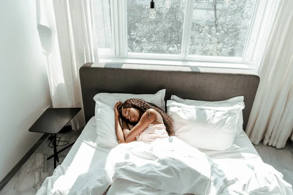 Vista de alto ângulo da mulher afro-americana dormindo na cama no quarto — Fotografia de Stock
