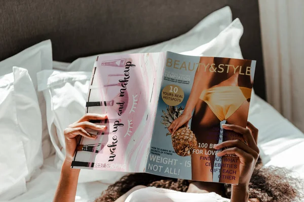 Afroamerikanerin liest Magazin auf Bett im Schlafzimmer — Stockfoto