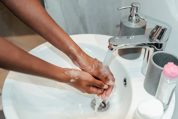 Vue recadrée de la femme afro-américaine se lavant les mains dans la salle de bain — Photo de stock