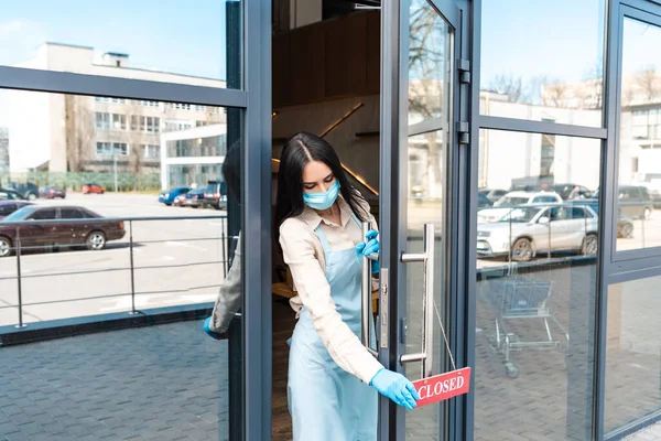 Cafébesitzer in medizinischer Maske berührt Karte mit geschlossenem Schriftzug auf der Straße — Stockfoto