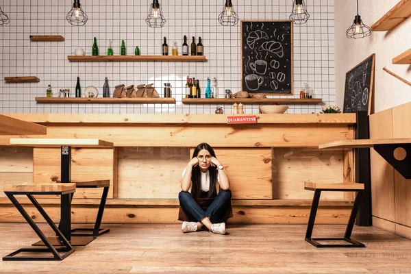 Cafe owner with crossed legs sitting on floor near table — Stock Photo
