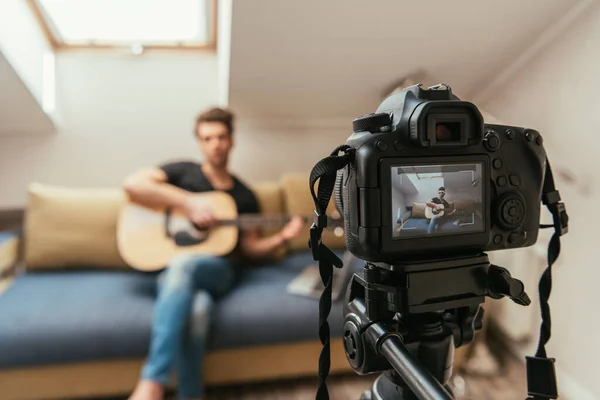 Selektiver Fokus des Videobloggers, der Gitarre spielt, während er auf die Digitalkamera blickt — Stockfoto
