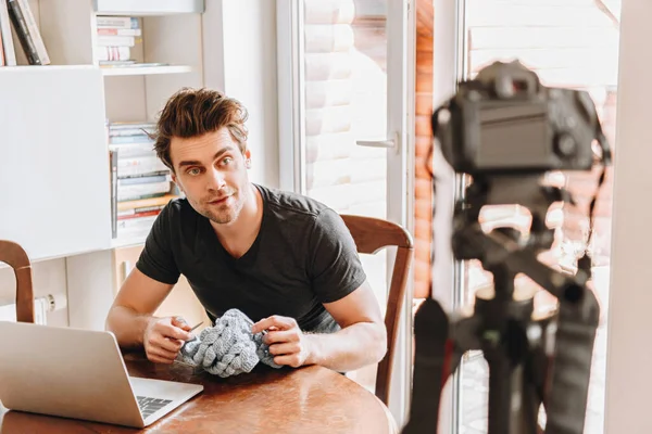 Selective focus of young vlogger knitting while looking at digital camera — Stock Photo