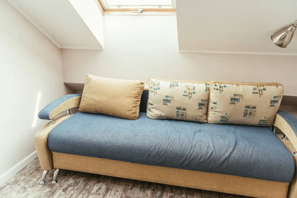 Уютная мансарда с окном и удобный диван с подушками — стоковое фото