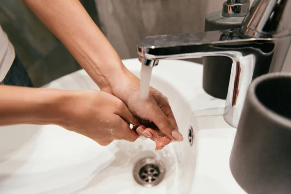 Vista recortada de la niña lavándose las manos en el lavabo en el baño durante la cuarentena - foto de stock